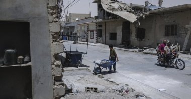 A boy carries bricks as he helps to restore a home, al-Qaryatayn, Syria, June 3, 2025. (AP Photo)