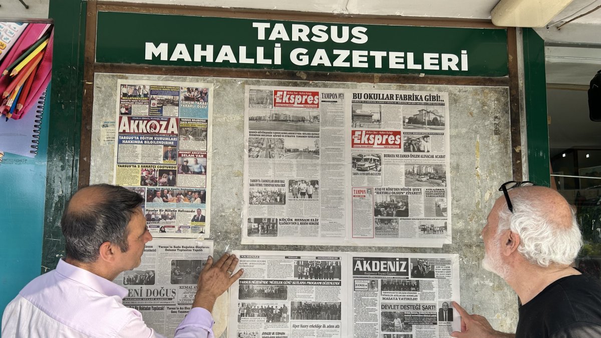 Two men read the daily news from a wall-mounted board, continuing a 48-year-old tradition of public newspaper displays in the town of Tarsus, Türkiye, June 8, 2025. (IHA Photo)