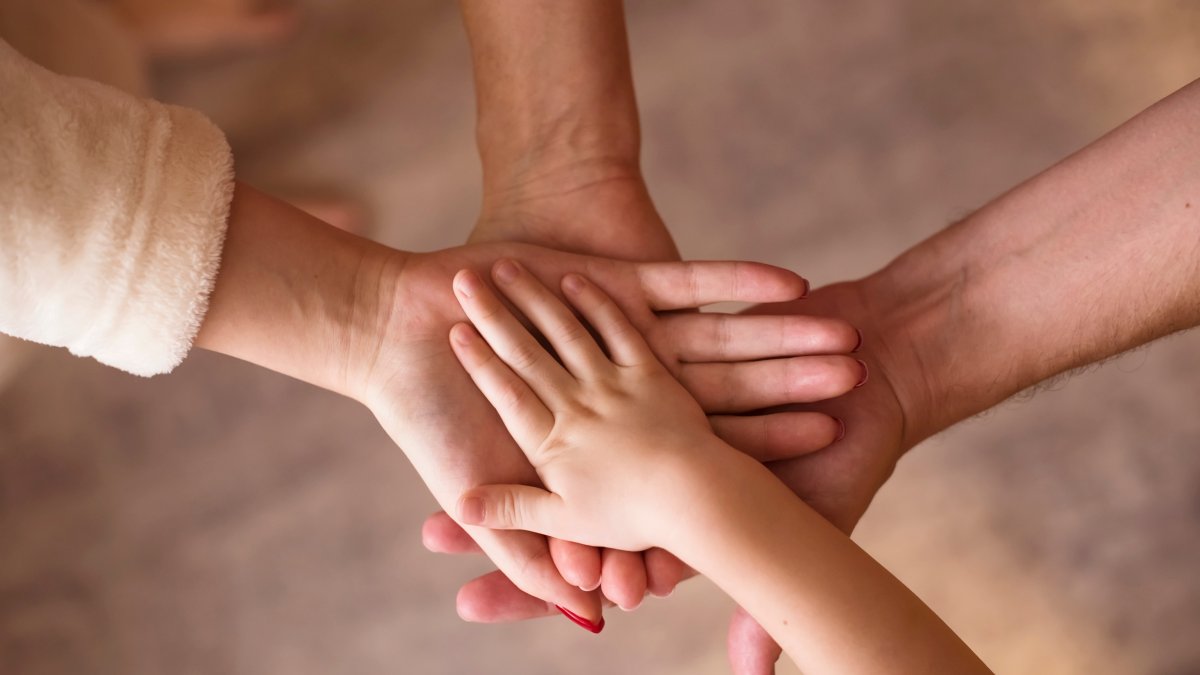 Four hands join together, symbolizing unity and strength in family bonds. (Shutterstock Photo)