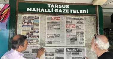 Two men read the daily news from a wall-mounted board, continuing a 48-year-old tradition of public newspaper displays in the town of Tarsus, Türkiye, June 8, 2025. (IHA Photo)