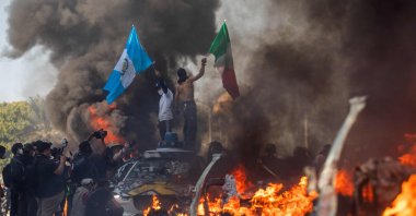 A man waves a Mexican flag while standing on top a self-driving car, in Los Angeles, California, U.S., June 08, 2025. (AFP Photo)