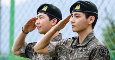 K-pop boy band BTS members RM (L) and V salute fans and members of the press at an outdoor sporting facility, Chuncheon, South Korea, June 10, 2025. (AFP Photo)