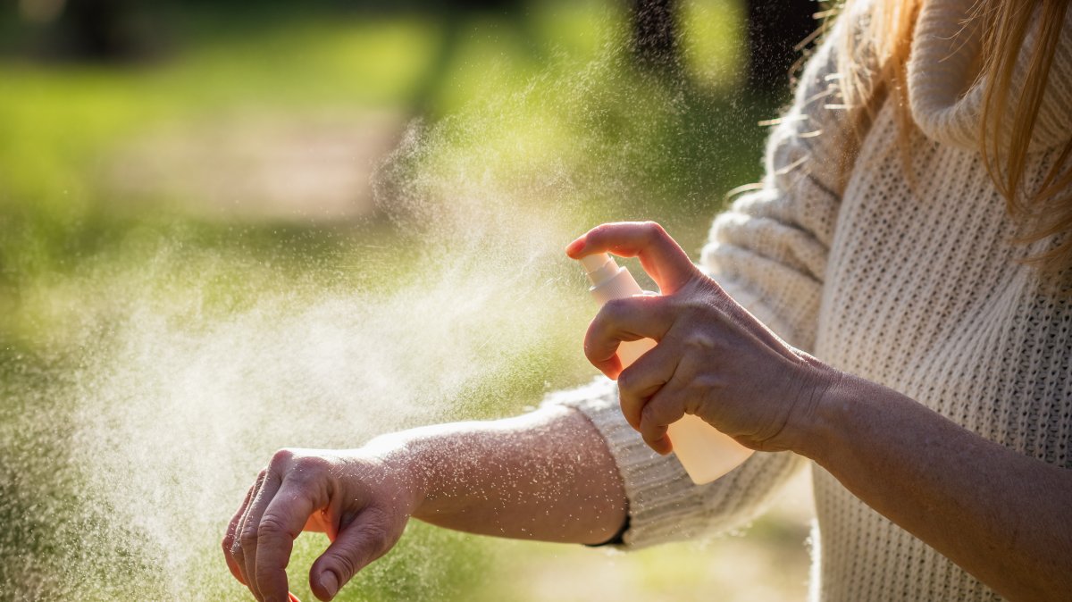 A person applies tick repellent spray before entering a wooded area to prevent bites. (Shutterstock Photo) 