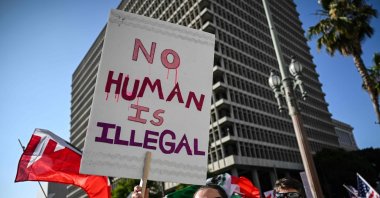A person holds up a sign during ongoing demonstrations in response to federal immigration operations near Los Angeles City Hall, Los Angeles, U.S., June 12, 2025. (AFP Photo)