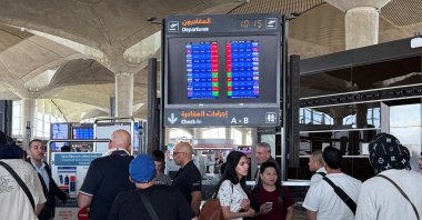 People stand in front of a flight information display screen showing information about delayed and canceled flights, Queen Alia International Airport in Amman, Jordan, June 13, 2025. (Reuters Photo)