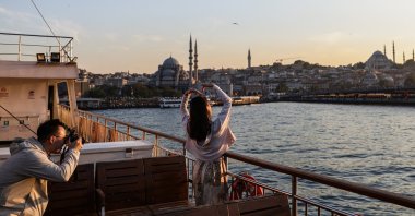 Tourists pose on a ferry backdropped by the Süleymaniye Mosque and the New Mosque in Eminönü during sunset in Istanbul, Türkiye, May 28, 2025. (EPA Photo)