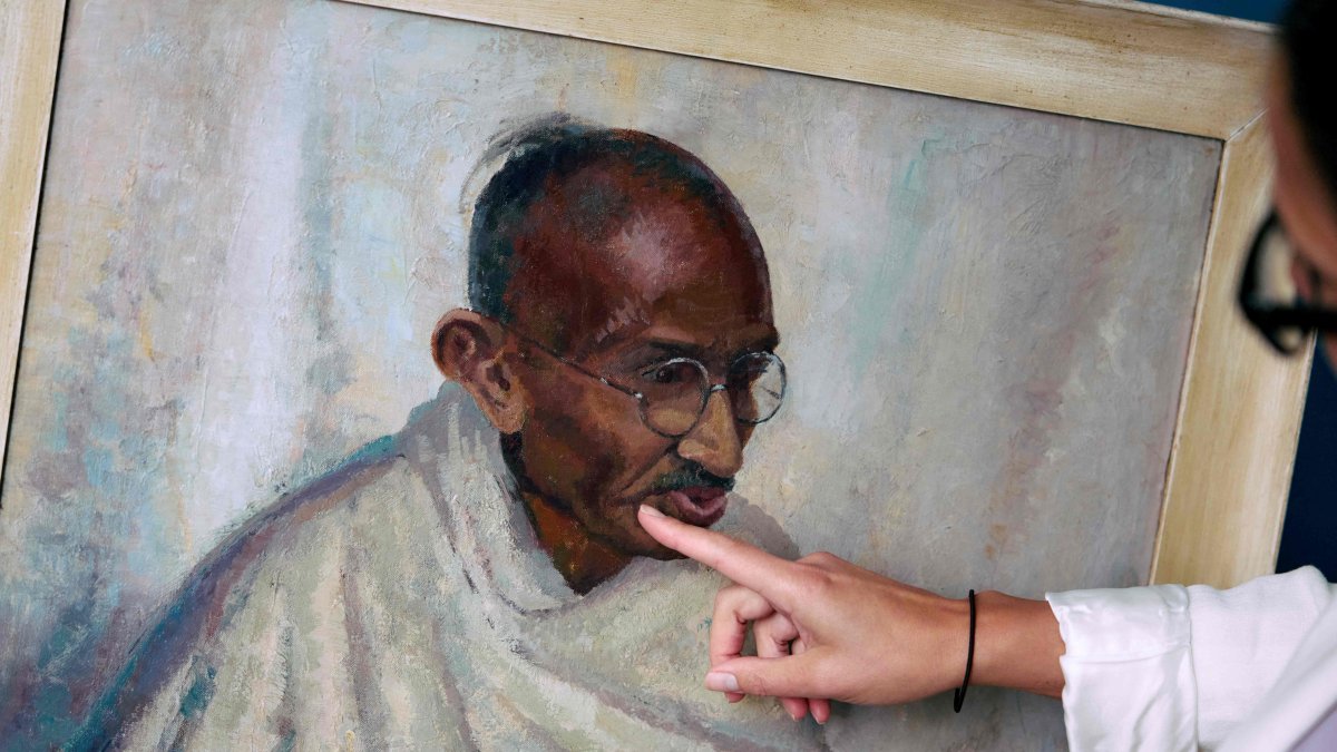 Rhyanon Demery, Bonhams head of sales for Travel and Exploration, points out the spot where the now-restored painting by British American artist Clare Leighton of Indian independence leader Mahatma Gandhi was once damaged, London, U.K., June 9, 2025. (AFP Photo)