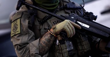 An Immigration and Customs Enforcement (ICE) Special Response Team (SRT) officer holds a grenade launcher for less lethal ammunition as protests continue in response to federal immigration operations at the Metropolitan Detention Center, Los Angeles, U.S., June 13, 2025. (AFP Photo)