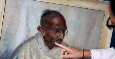 Rhyanon Demery, Bonhams head of sales for Travel and Exploration, points out the spot where the now-restored painting by British American artist Clare Leighton of Indian independence leader Mahatma Gandhi was once damaged, London, U.K., June 9, 2025. (AFP Photo)