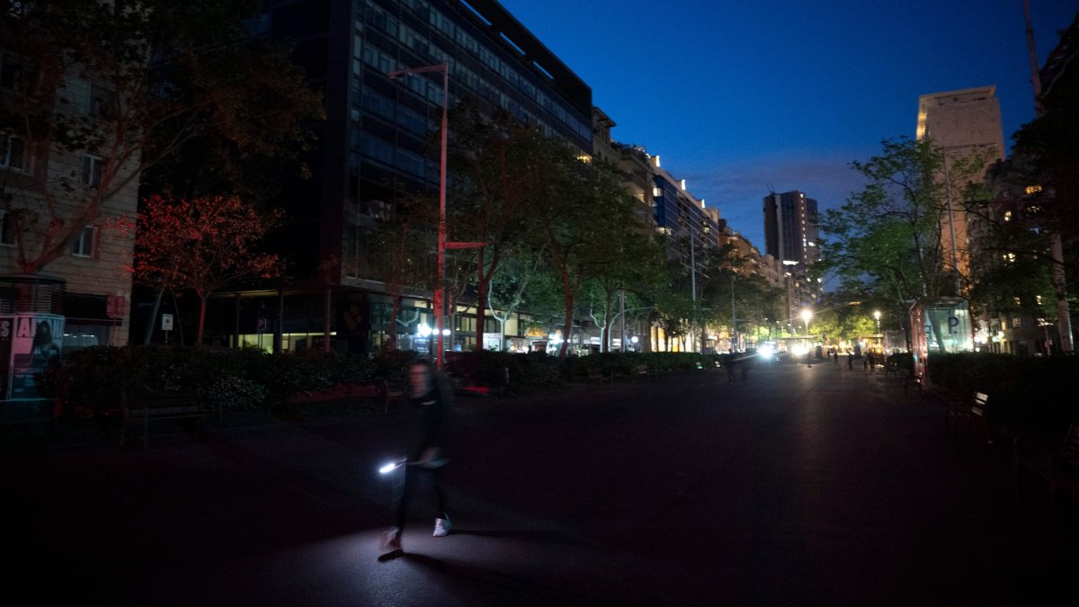 A pedestrian uses a flashlight to walk in a street of Barcelona, without electricity, following a massive power cut affecting the entire Iberian peninsula and the south of France, April 28, 2025. (AFP Photo)