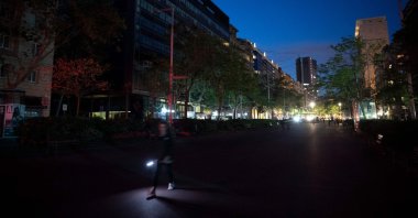 A pedestrian uses a flashlight to walk in a street of Barcelona, without electricity, following a massive power cut affecting the entire Iberian peninsula and the south of France, April 28, 2025. (AFP Photo)