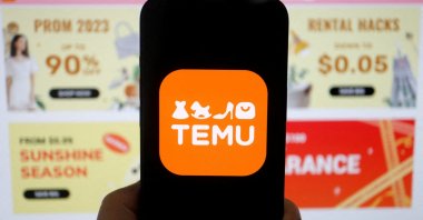 The logo of Temu, an e-commerce platform owned by PDD Holdings, is seen on a mobile phone displayed in front of its website, in this illustration picture taken April 26, 2023. (Reuters Photo)