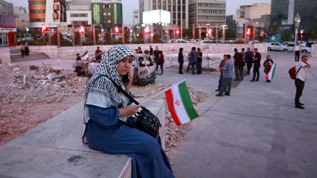 An Iranian woman holding a national flag listens to a traditional music band performing in solidarity with the Iranian people in Hafte-Tir square in central Tehran, Iran, June 23, 2025. (EPA Photo)