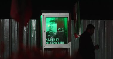 An Iranian man walks past an image of Mohammad Bakeri, late commander of the Revolutionary Guards Air Force, with the slogan "Killed by Netanyahu" at a memorial for those killed by Israel, Hafteh-tir Square, Tehran, Iran, June 23, 2025. (AFP Photo)