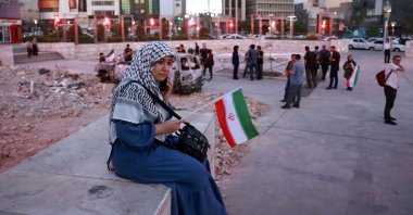 An Iranian woman holding a national flag listens to a traditional music band performing in solidarity with the Iranian people in Hafte-Tir square in central Tehran, Iran, June 23, 2025. (EPA Photo)