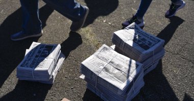 Supporters walk past stacks of newspapers, Butler, Pennsylvania, U.S., Oct. 5, 2024. (AP Photo)