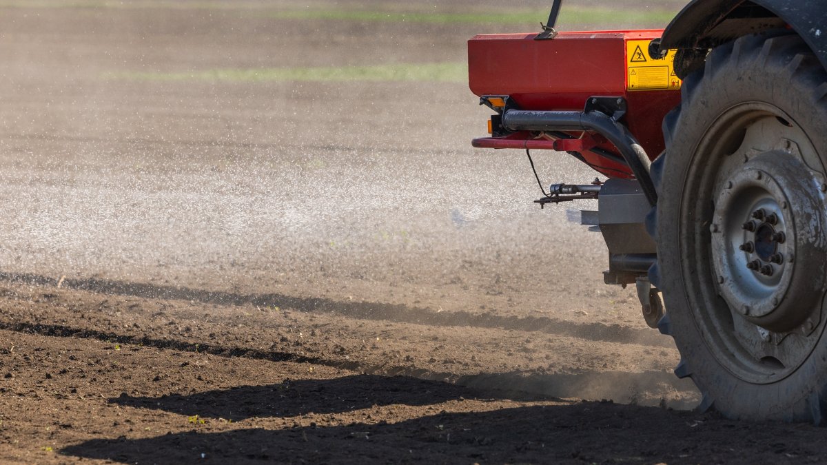 A tractor distributes artificial fertilizers across farmland. (Shutterstock Photo)