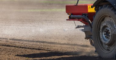 A tractor distributes artificial fertilizers across farmland. (Shutterstock Photo)
