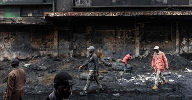 Residents walk past a shopping center that was vandalized and torched during deadly protests marking one year since the storming of Parliament in anti-tax demonstrations, Nairobi, Kenya, June 26, 2025. (AFP Photo)