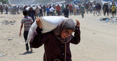 A Palestinian carries a sack of flour as people gather to receive aid supplies in Khan Younis, in the southern Gaza Strip, June 26, 2025. (Reuters Photo)