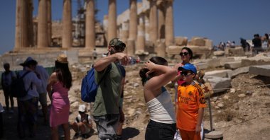 A man tries to cool a girl with water during their visit to the Parthenon temple atop the Acropolis hill, as a heatwave hits Athens, Greece, June 27, 2025. (Reuters Photo)