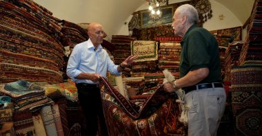 U.S. Ambassador to Türkiye and Special Envoy for Syria Thomas J. Barrack (L) negotiates for a rug with a dealer, Izmir, western Türkiye, June 29, 2025. (AA Photo)
