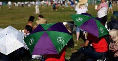 Spectators sit on the lawn and take cover under umbrellas from the sun ahead of day one of Wimbledon at the All England Lawn Tennis and Croquet Club, London, U.K., June 30, 2025. (Reuters Photo)