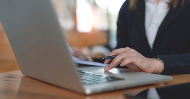 A woman engages in online learning using her laptop, accessing distance education courses. (Shutterstock Photo)