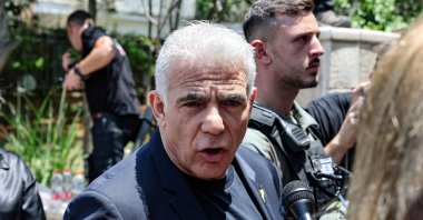 Israel&#039;s opposition leader and member of Parliament, Yair Lapid, speaks to a journalist as he visits the Ramat Aviv area in Tel Aviv, following an Iranian strike that hit the residential neighborhood, June 22, 2025. (AFP Photo)