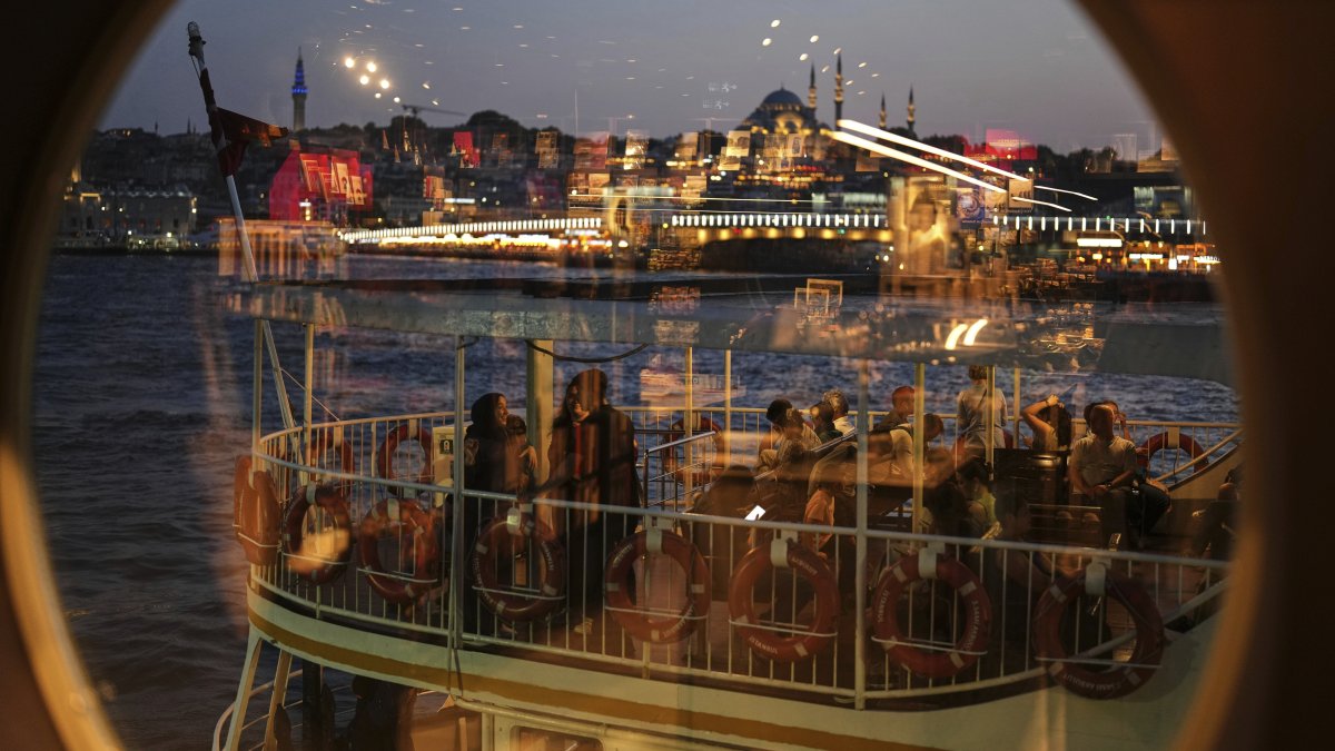 With the Süleymaniye Mosque in the background, passengers, seen through a window, board a ferry before departing from the Karaköy terminal, Istanbul, Türkiye, June 13, 2025. (AP Photo)