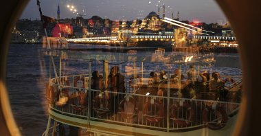 With the Süleymaniye Mosque in the background, passengers, seen through a window, board a ferry before departing from the Karaköy terminal, Istanbul, Türkiye, June 13, 2025. (AP Photo)