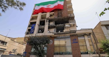 A woman walks past a residential building that was hit in an Israeli strike covered with a big Iranian flag, in Tehran, Iran, June 25, 2025. (AFP Photo)
