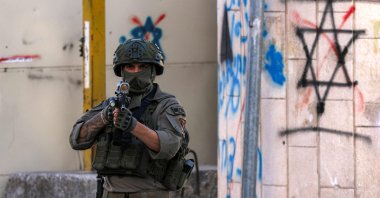 An Israeli soldier stands guard as Israeli settlers tour in the old city-center and market of the Palestinian city of Hebron in the occupied West Bank, June 28, 2025. (AFP Photo)