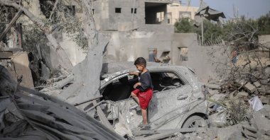 A Palestinian boy checks the wreckage of a car at the rubble of a residential house in Deir el-Balah in the central Gaza Strip, July 1, 2025. (AFP Photo)