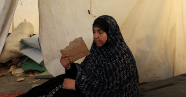 A Palestinian woman, displaced by the Israeli offensive, fans herself with a piece of cardboard as she shelters in a tent amid summer heat, in Gaza City, central Gaza, Palestine, July 3, 2025. (Reuters Photo)