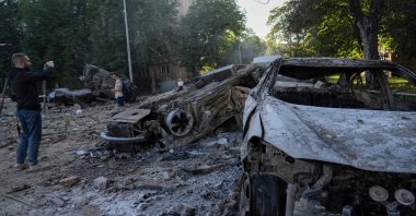 Men stand next to the wreckage of cars following mass Russian drone and missile strikes amid the Russian invasion of Ukraine, Kyiv, Ukraine, July 4, 2025. (AFP Photo)