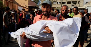 A man carries the body of a child during the funeral of Palestinians killed overnight in Israeli attacks on a tent and on people seeking aid, according to Gaza's Health Ministry, at Nasser Hospital, Khan Younis, Gaza Strip, Palestine, July 4, 2025. (Reuters Photo)