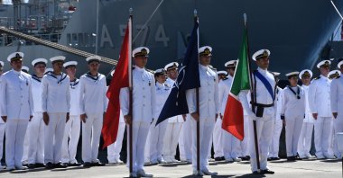 Turkish and Italian navy officers hold the flags of Türkiye, NATO and Italy (L to R), during a mission transfer ceremony in the Marmaris district of western Muğla province, Türkiye, July 4, 2025. (AA Photo)