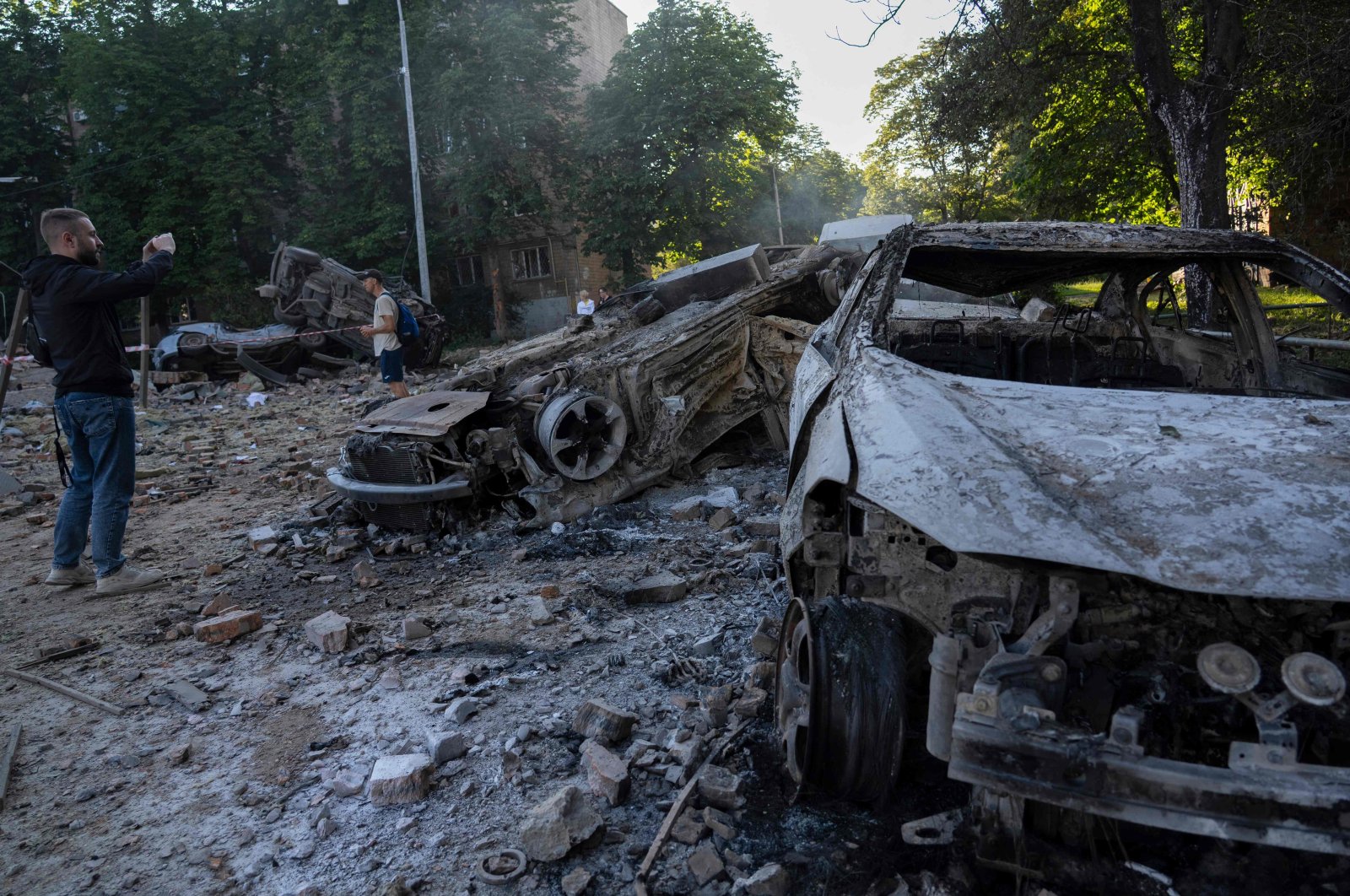 Men stand next to the wreckage of cars following mass Russian drone and missile strikes amid the Russian invasion of Ukraine, Kyiv, Ukraine, July 4, 2025. (AFP Photo)