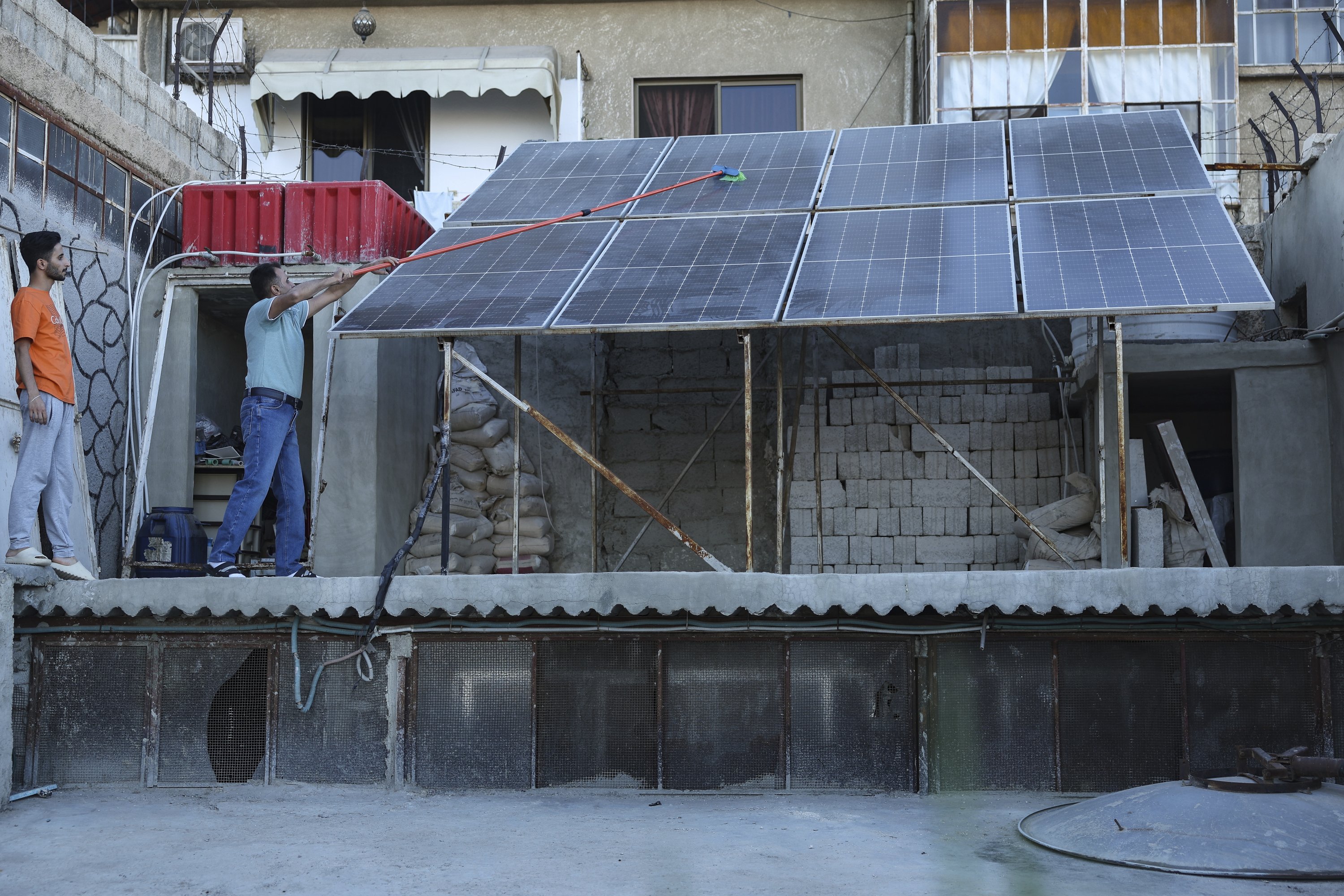 A Syrian man, Abdul Razzaq al-Jenan, cleans solar panels on his house roof, Damascus, Syria, June 29, 2025. (AP Photo)