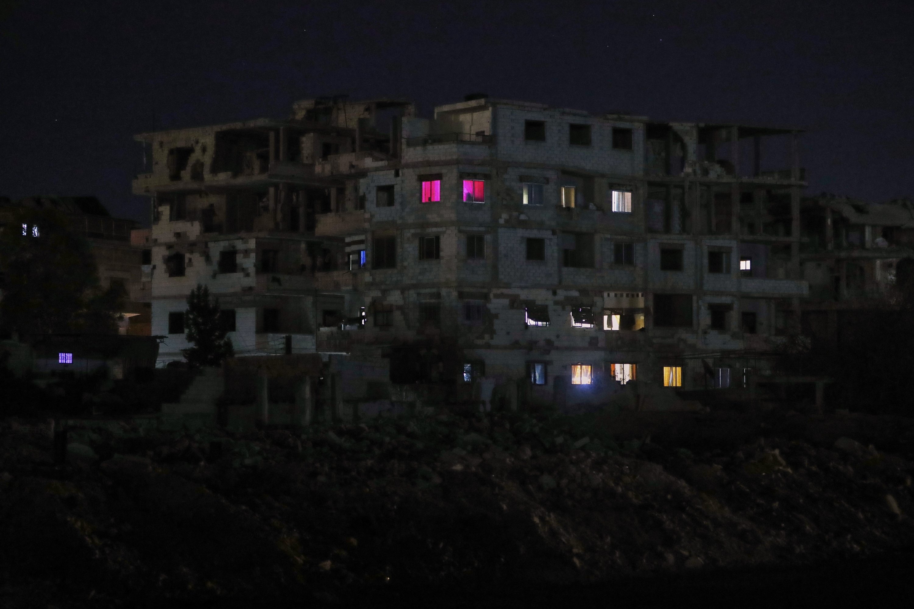 Lights illuminate a few windows of a damaged building, Damascus, Syria, March 27, 2025. (AP Photo)