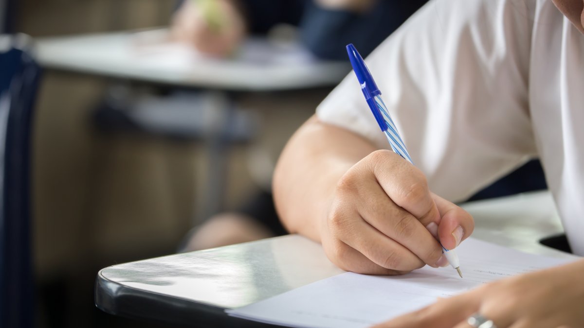A student writes answers during an exam in a classroom. (Shutterstock Photo)