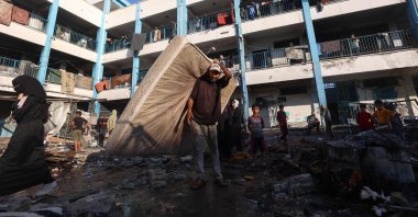 A Palestinian man carries a mattress after an Israeli strike hit a school sheltering displaced Palestinians in the al-Bureij camp in the central Gaza Strip, Palestine, July 8, 2025. (AFP Photo)