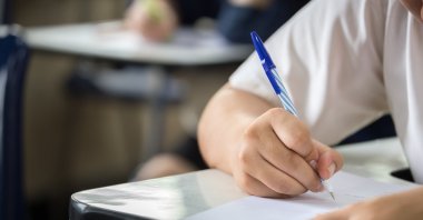 A student writes answers during an exam in a classroom. (Shutterstock Photo)