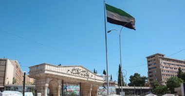 People walk near the Syrian flag, Aleppo, Syria, May 14, 2025. (Reuters Photo)