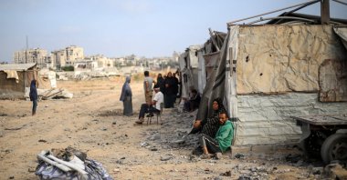 Palestinians sit in front of their makeshift home in the Bureij refugee camp in the central Gaza Strip on July 10, 2025. (Photo by Eyad BABA / AFP)