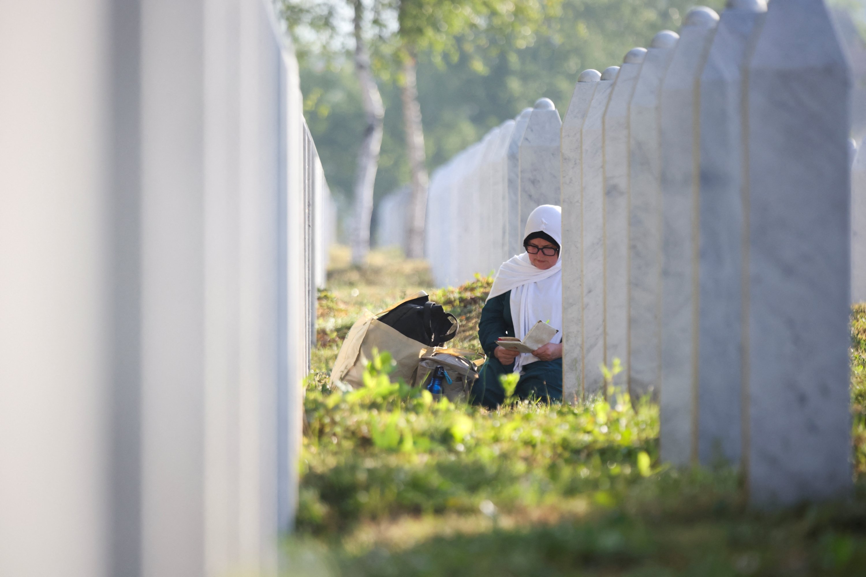 A Bosnian Muslim woman reads as she sits amid grave stones of victims killed during the Srebrenica genocide, at the memorial cemetery in the village of Potocari, near the eastern town of Srebrenica, Bosnia-Herzegovina, July 11, 2025. (Reuters Photo)
