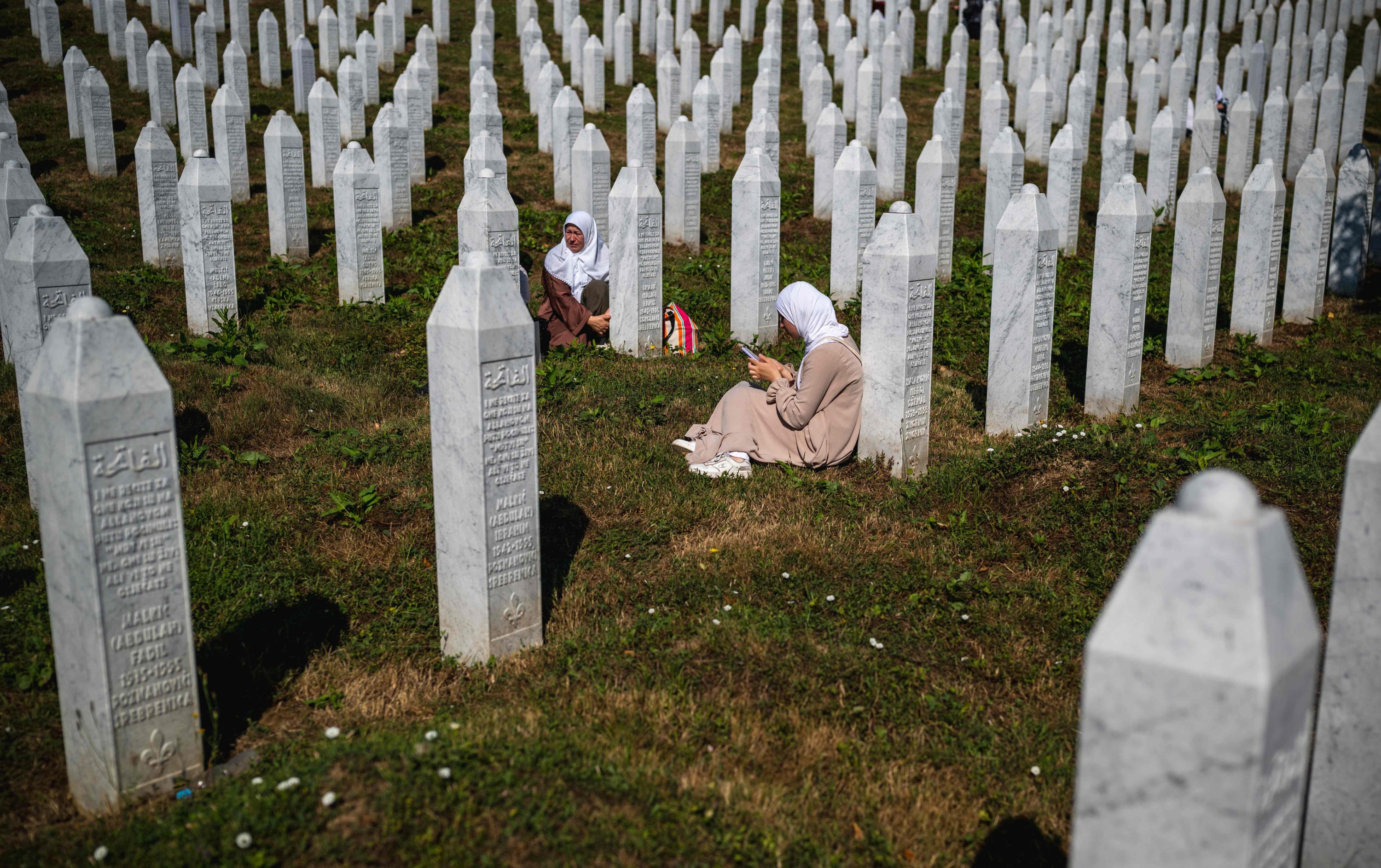 Women sit near grave stones at the memorial cemetery in the village of Potocari, near the eastern Bosnian town of Srebrenica, July 11, 2025. (AFP Photo)