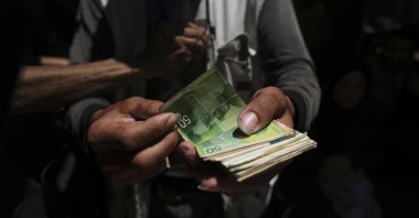 A Palestinian vegetable merchant shows worn-out Israeli currency, Gaza City, Palestine, July 9, 2025. (AP Photo)