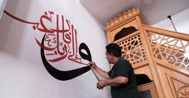 Mehmet Emin Deniz hand-paints Quranic calligraphy on a mosque wall using traditional techniques, Van, Türkiye, July 4, 2025. (AA Photo)